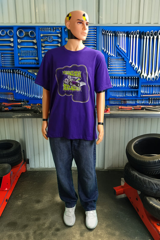 Crash test dummy mannequin in a workshop setting wearing a purple t-shirt with green and purple illustration of a retro coupe with a small engine and a giant turbo charger spinning it's wheels in front of a brick wall with a crash test dummy driving and graffiti styled text that reads Displacement Replacement.